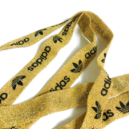 Greyish golden yellow binding with black logo and word adidas by metre - width 20 mm